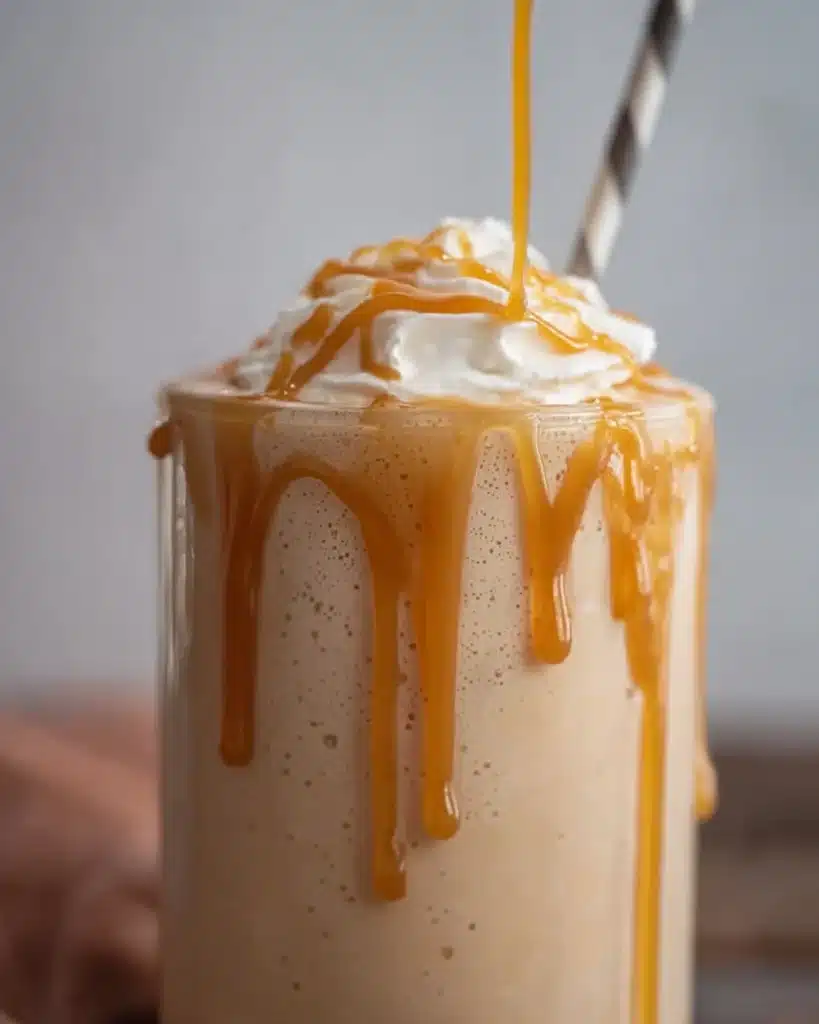 Creamy caramel frappe with whipped cream and caramel drizzle in a tall glass