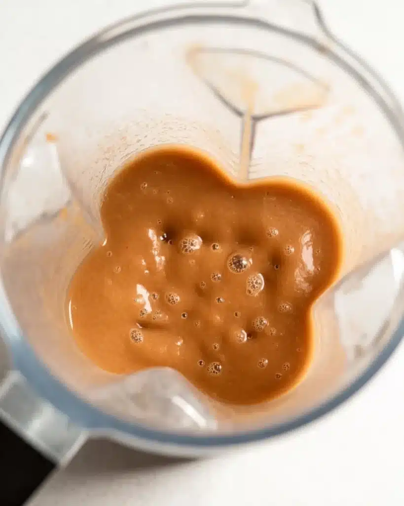 Blended apple butter in a blender jar with smooth caramel texture