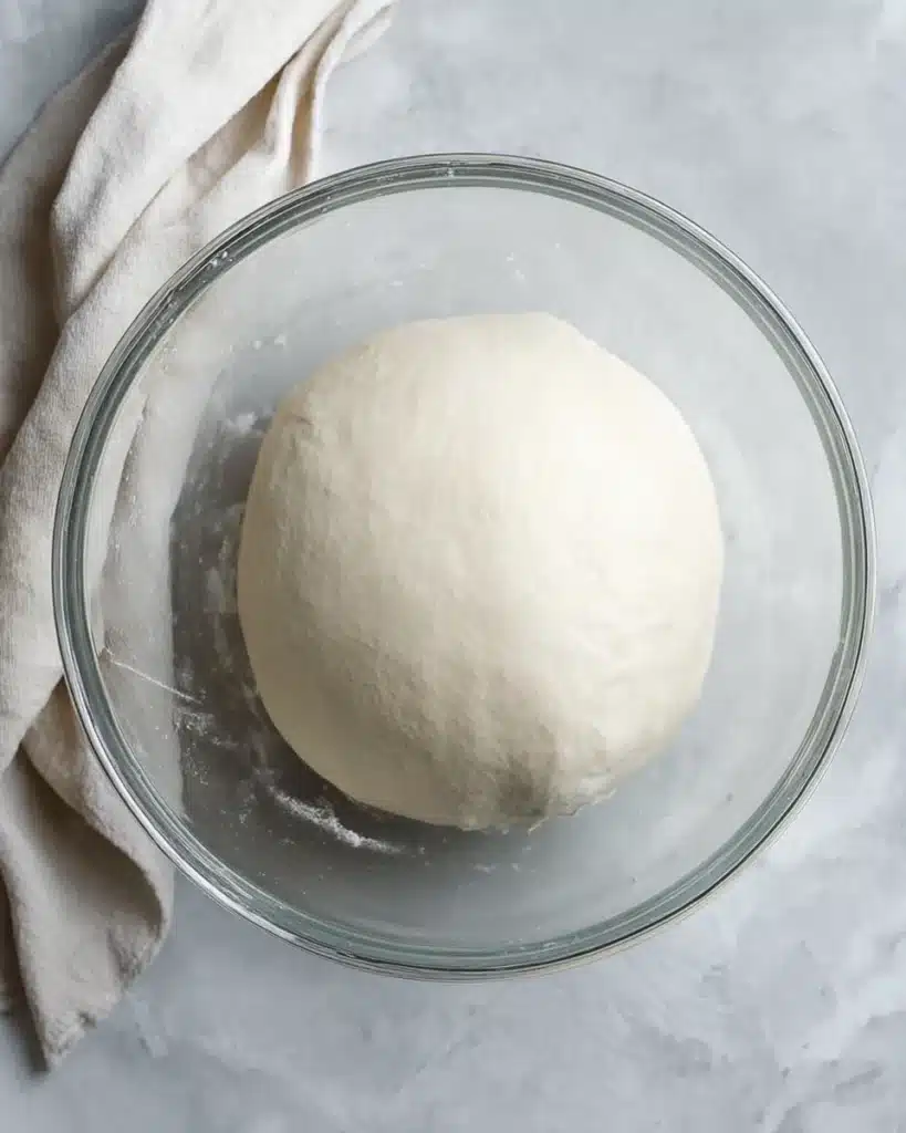 Sourdough Hamburger or Hot Dog Buns (Soft, Flavorful, and Easy to Make) 3 Risen sourdough dough in glass bowl after kneading