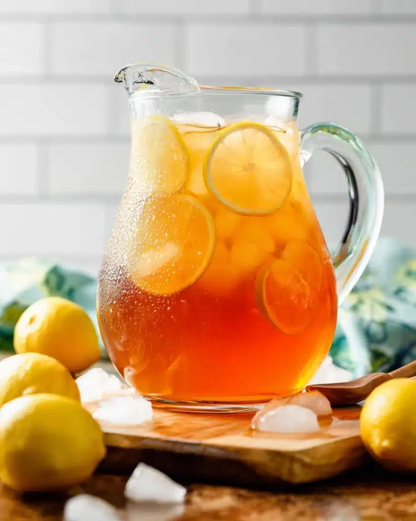 Sweet Tea Recipe – The Perfect Refreshing Southern Drink 1 Glass pitcher of sweet tea with lemon slices and ice on wooden board
