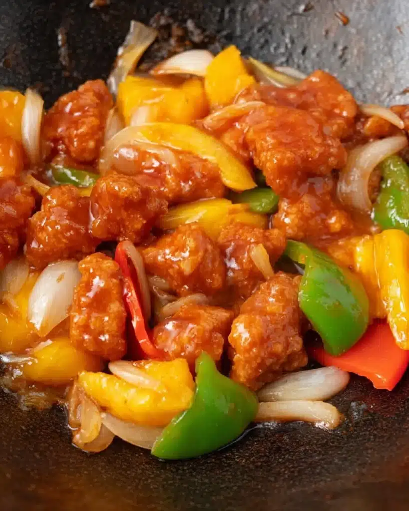 Sweet and Sour Chicken Recipe (Better Than Takeout!) 7 Sweet and sour chicken with peppers, onions, and pineapple cooking in a wok