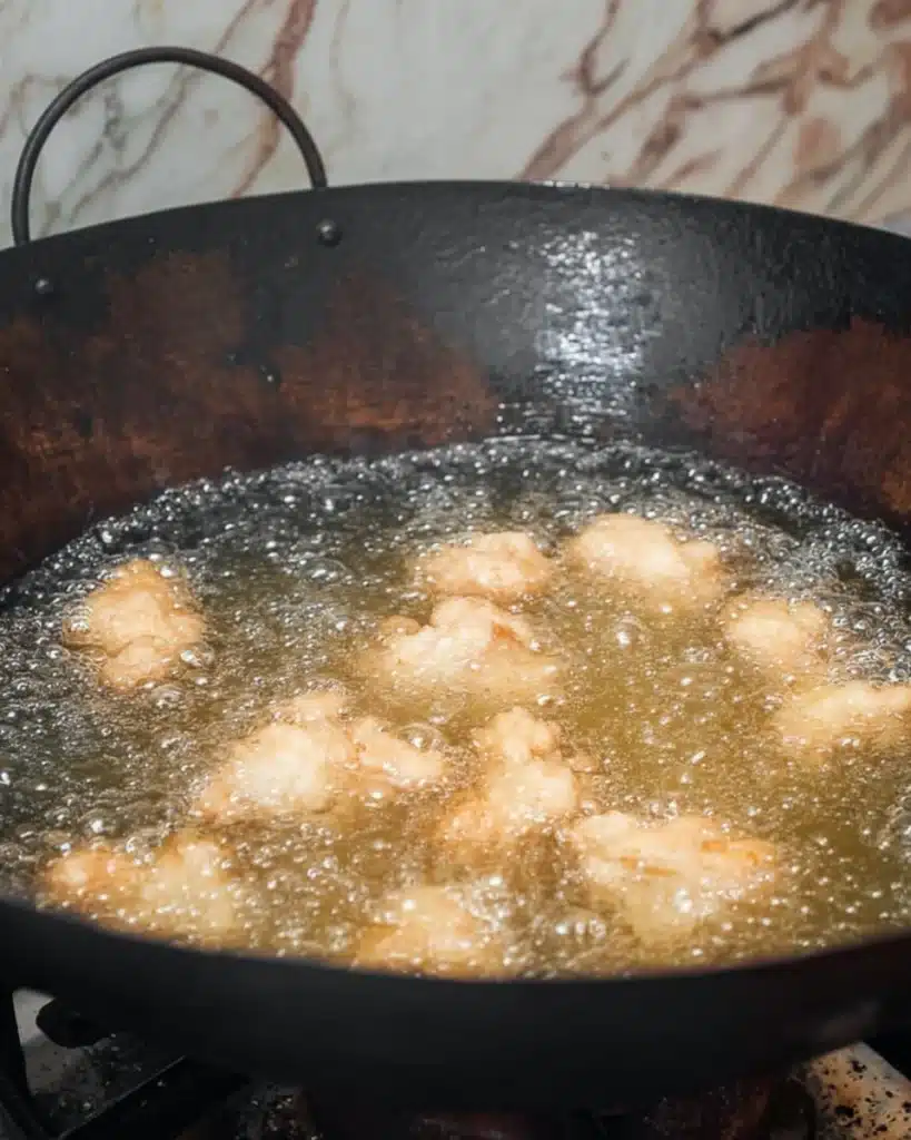 Sweet and Sour Chicken Recipe (Better Than Takeout!) 5 Chicken frying in hot oil inside a black wok for sweet and sour chicken recipe