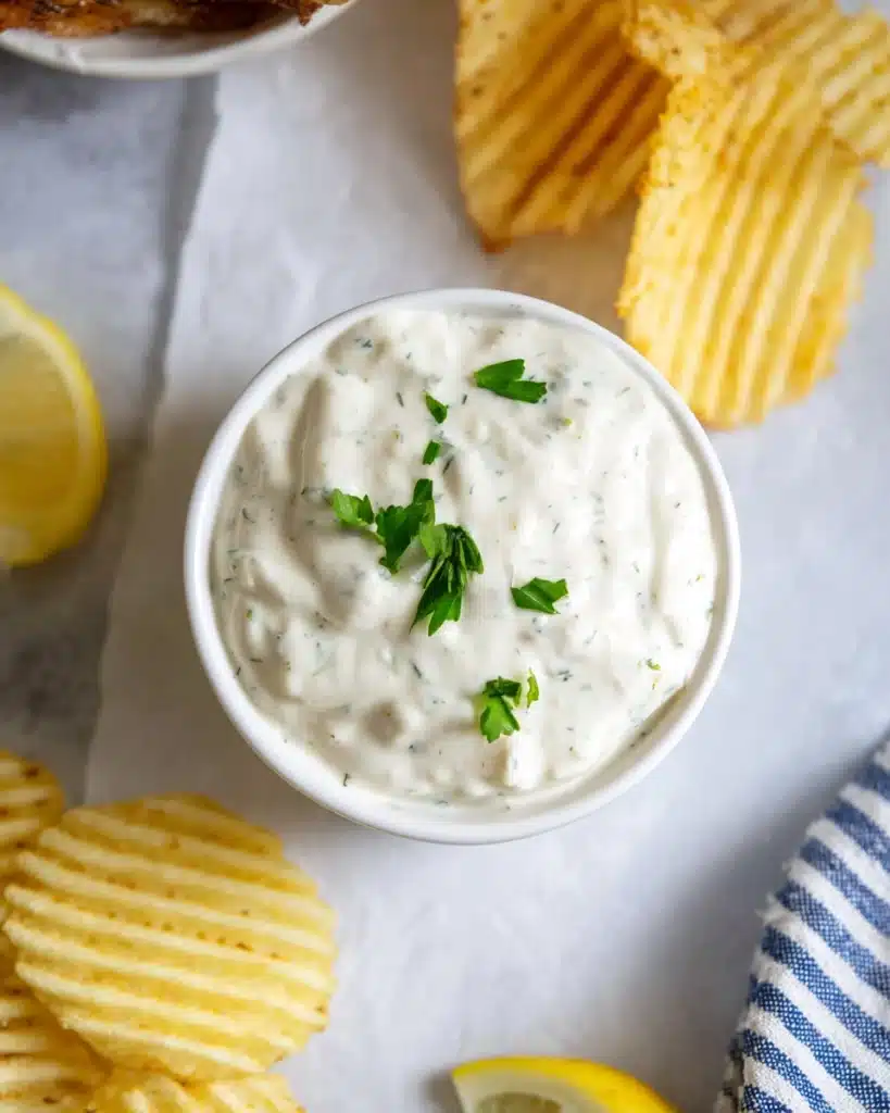 Easy Homemade Tartar Sauce for Seafood Lovers (5-Minute Recipe) 4 Creamy homemade tartar sauce in a white bowl with lemon and chips