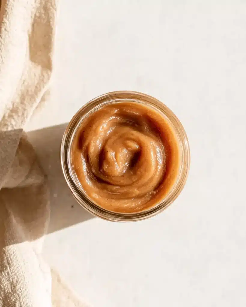 Homemade slow cooker apple butter in a glass jar with a smooth, glossy texture