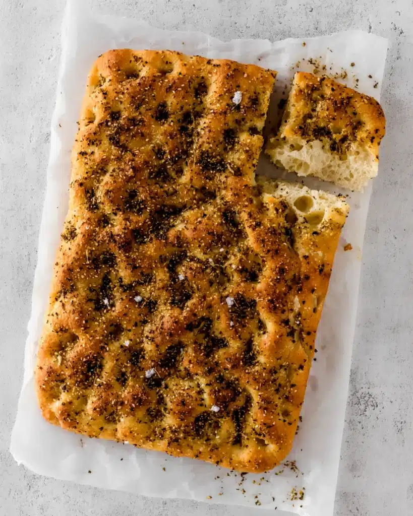 Easy No-Knead Za’atar Focaccia Bread (Appetizer Recipes) 4 Golden za’atar focaccia bread on parchment paper with a torn piece