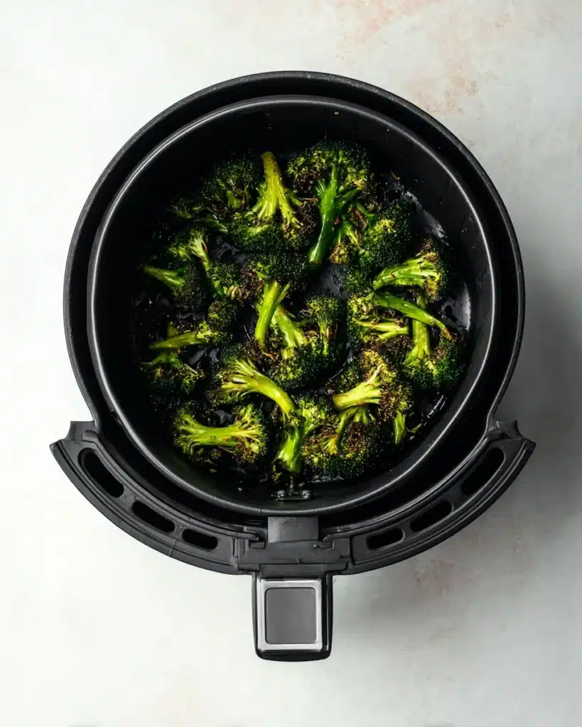 Air Fryer Broccoli (Crispy, Flavorful & Ready in Minutes) 2 Crispy roasted air fryer broccoli in the basket showing browned edges and vibrant green stems