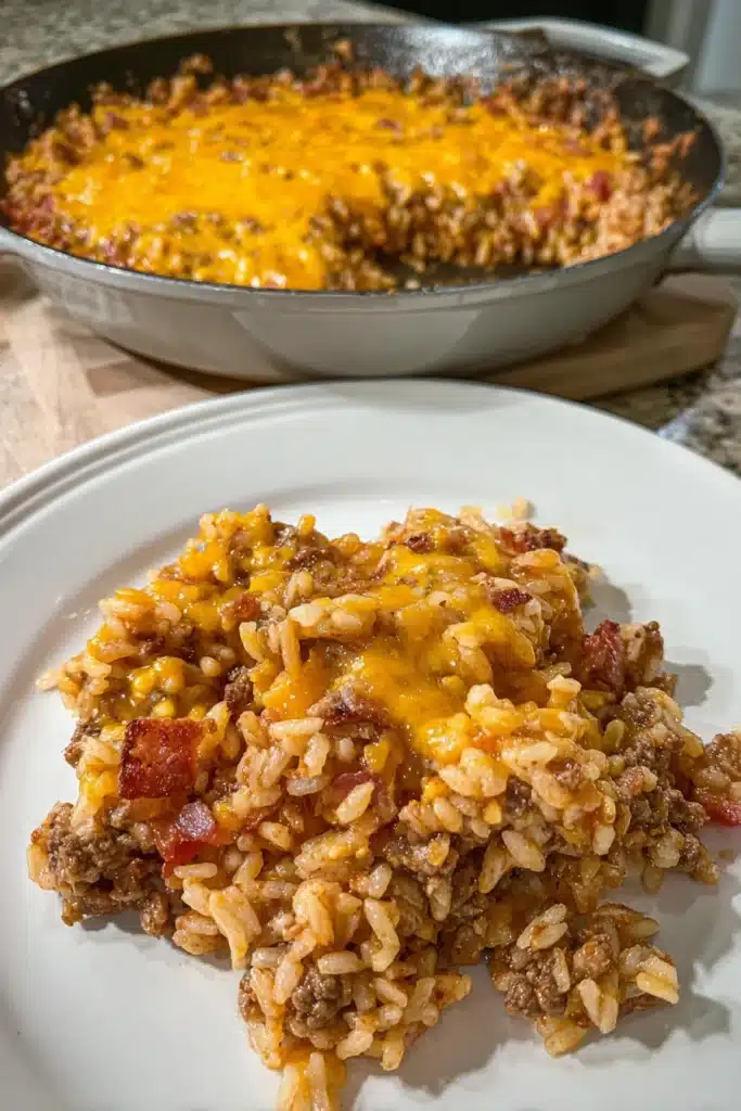 Bacon Cheeseburger Rice Skillet 1 Plated bacon cheeseburger rice skillet with melted cheddar and bacon on white dish