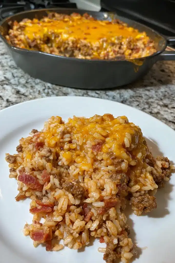 Bacon Cheeseburger Rice Skillet 4 Plated bacon cheeseburger rice skillet with melted cheddar and bacon on white dish