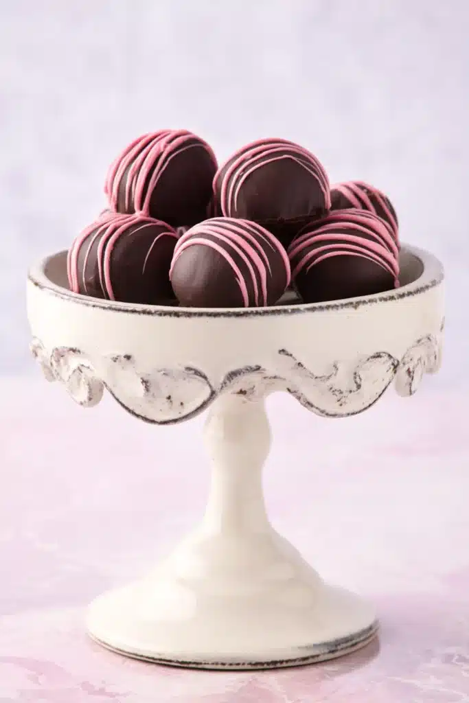 Chocolate Raspberry Truffles 1 Chocolate raspberry truffles with pink drizzle on white dessert stand