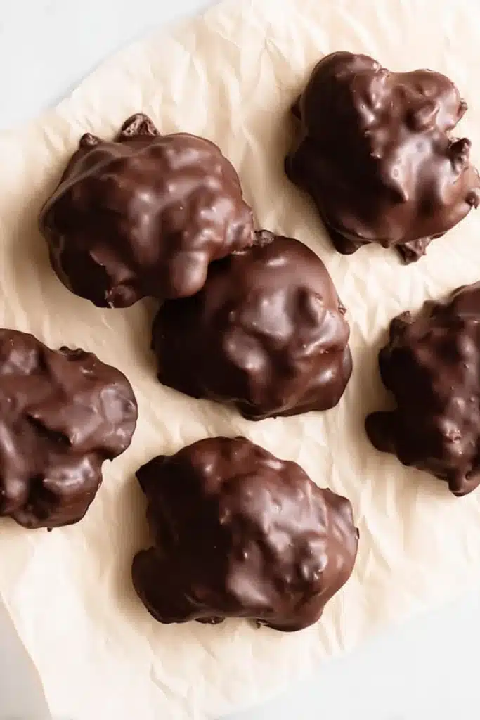 Chocolate Strawberry Yogurt Clusters (Healthy, Easy, No-Bake Snack!) 5 Chocolate-coated strawberry yogurt clusters on parchment paper
