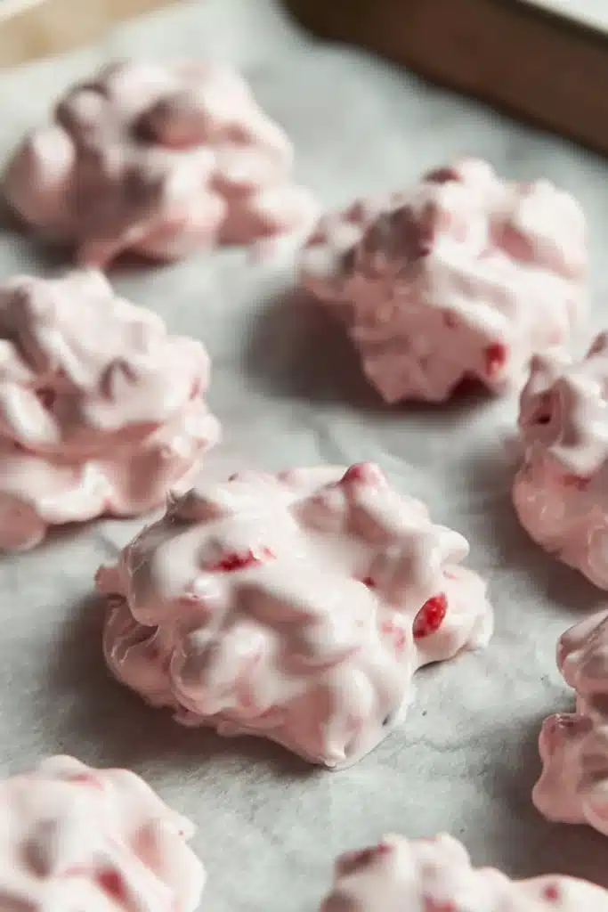 Chocolate Strawberry Yogurt Clusters (Healthy, Easy, No-Bake Snack!) 4 Uncoated strawberry yogurt clusters on parchment before freezing