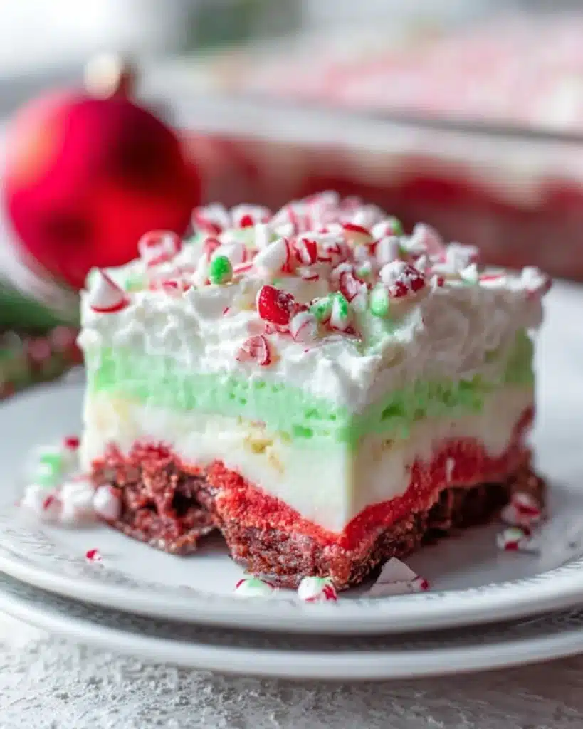 Christmas Lasagna Dessert 1 Christmas lasagna dessert with red, green, and white layers topped with whipped cream and peppermint