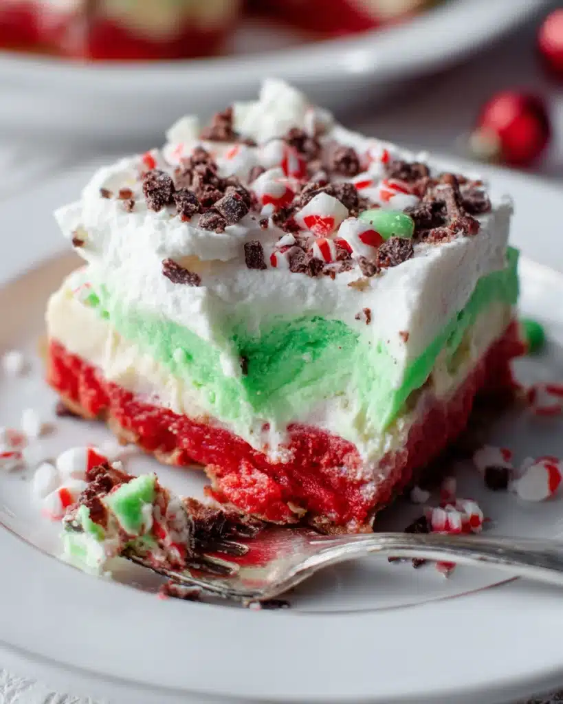 Christmas Lasagna Dessert 4 Slice of Christmas lasagna dessert with red, green, and white layers and peppermint topping