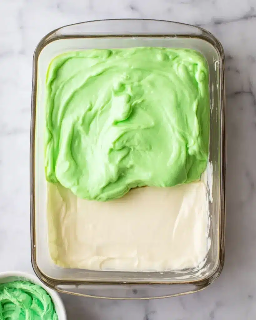 Christmas Lasagna Dessert 2 Green pudding layer being spread over cream layer in Christmas lasagna dessert