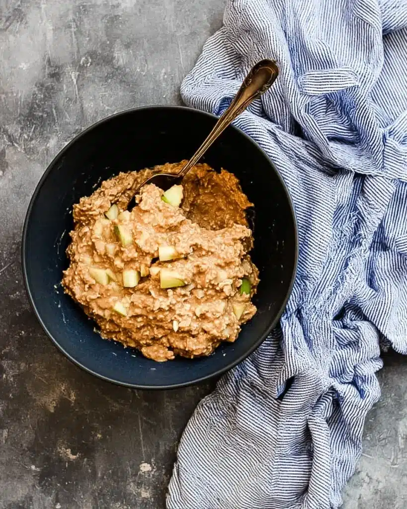 Thick cinnamon apple oatmeal muffin batter with apples and oats in a bowl