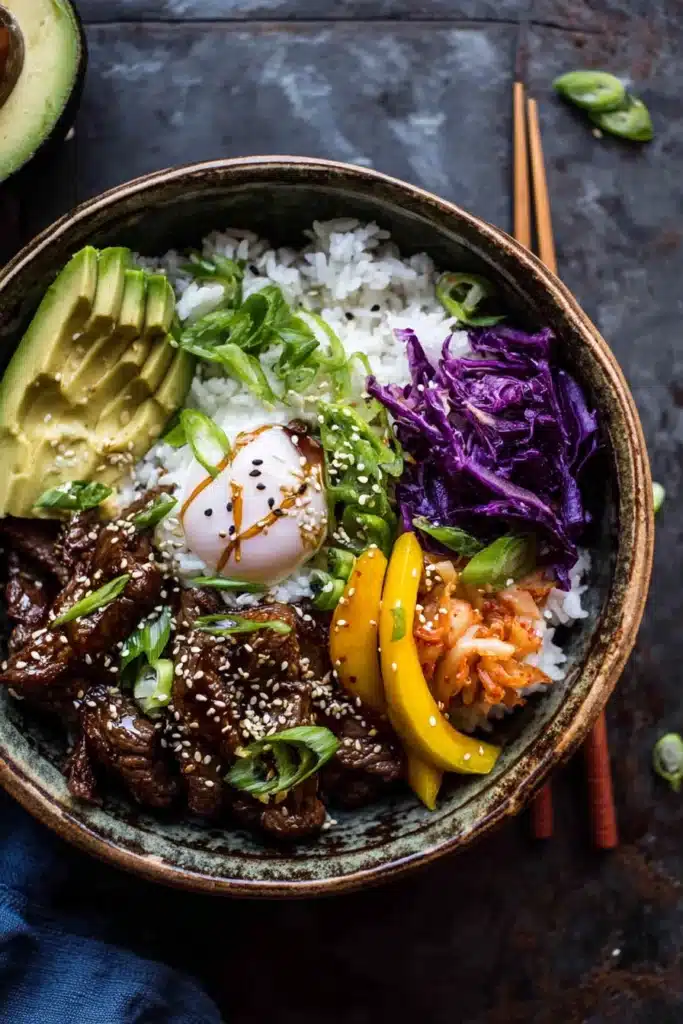 Korean BBQ steak rice bowl with avocado, kimchi, mango, and poached egg