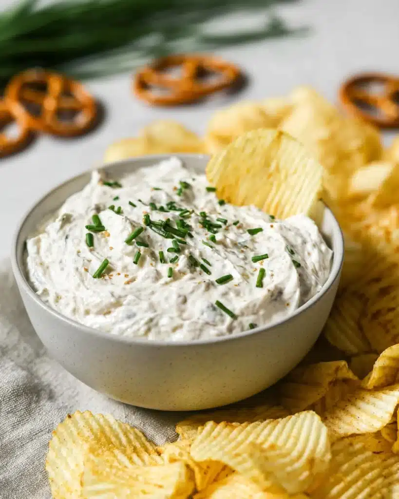 Sour Cream and Onion Dip 1 Creamy sour cream and onion dip with chives and potato chips in a bowl
