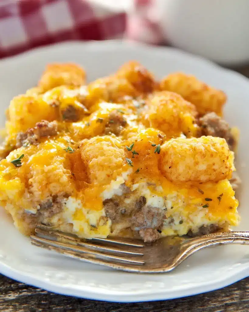 Tater Tot Sausage Breakfast Casserole – The Ultimate Comfort Breakfast 1 Tater Tot Sausage Breakfast Casserole with melted cheese and golden tater tots on a white plate
