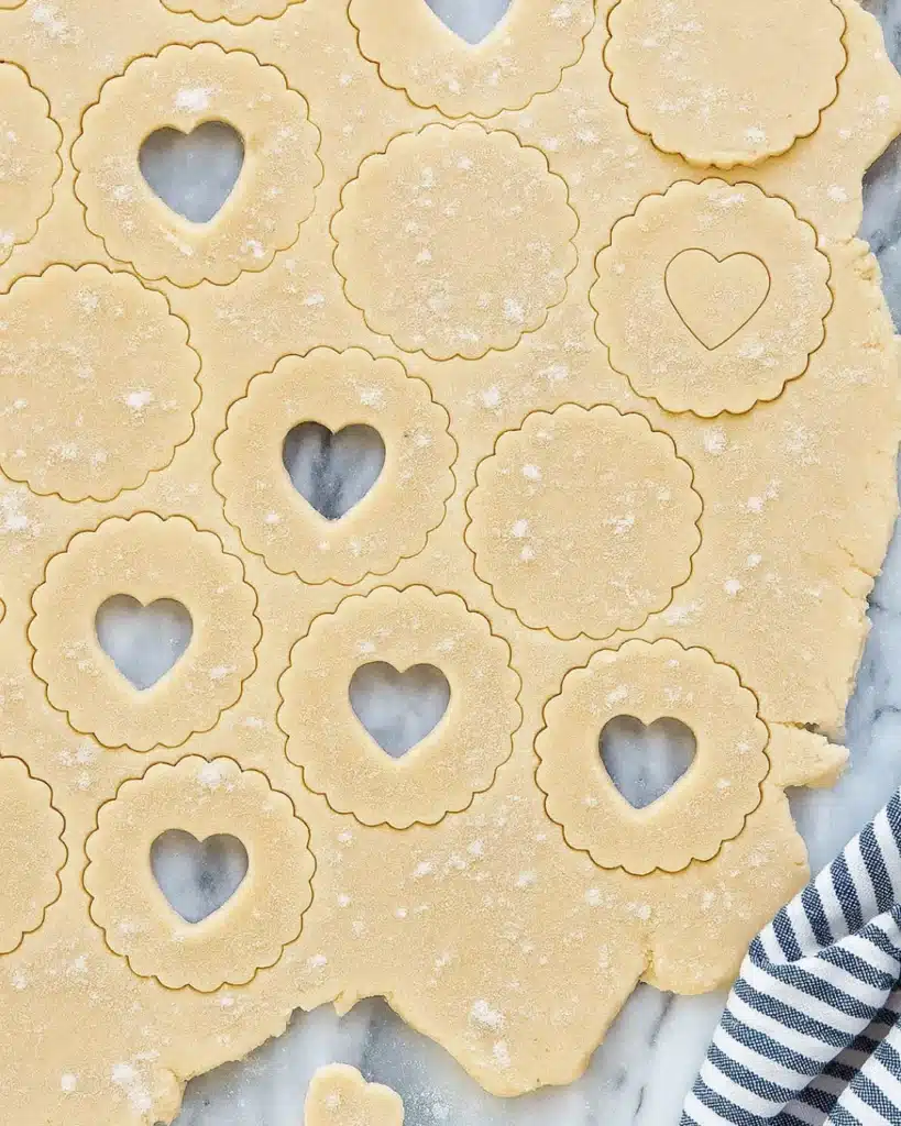 Rolled Linzer cookie dough with scalloped edges and heart-shaped cutouts