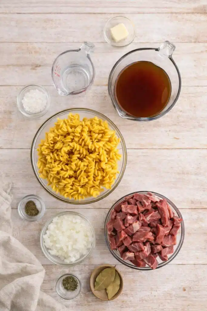 Beef tips and noodles ingredients arranged on light surface