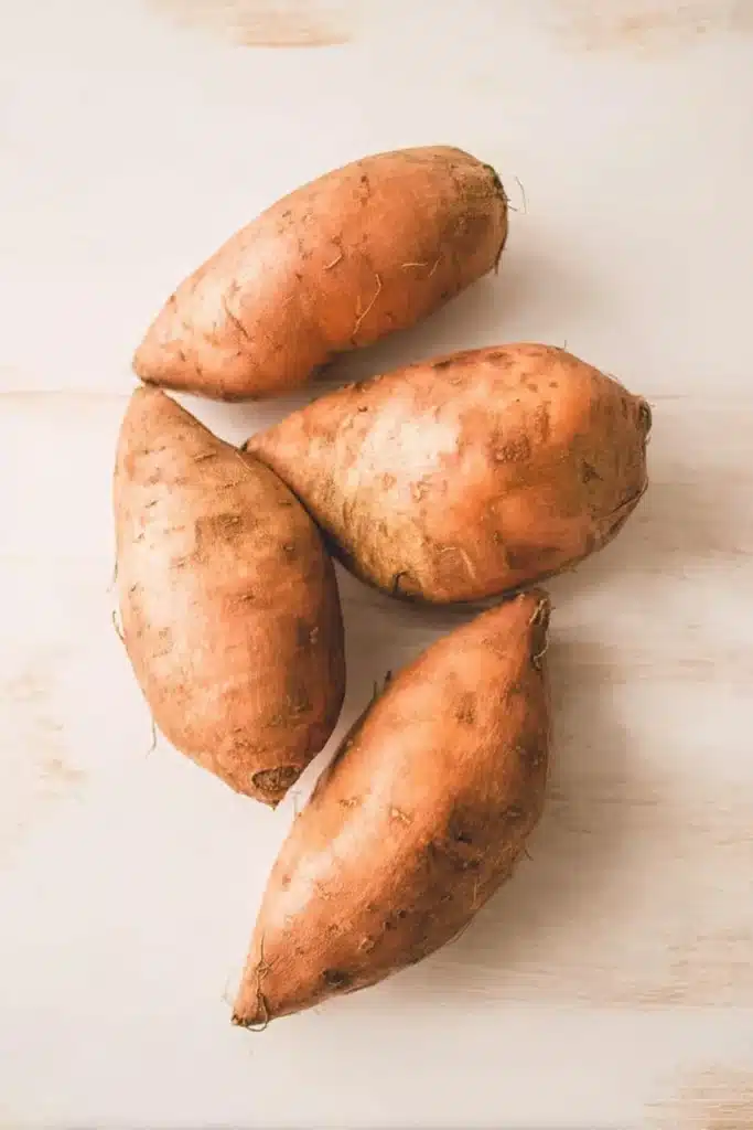 Chicken and Broccoli Stuffed Sweet Potatoes (Easy, Healthy Chicken Dinner Recipe) 2 Raw sweet potatoes on a light marble surface for chicken and broccoli stuffed sweet potatoes recipe