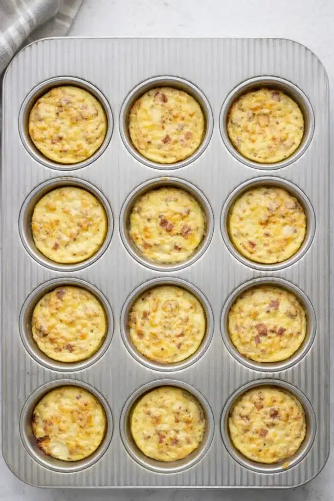 Cottage Cheese Egg Bites 2 Freshly baked cottage cheese egg bites in a muffin pan with bacon and cheese