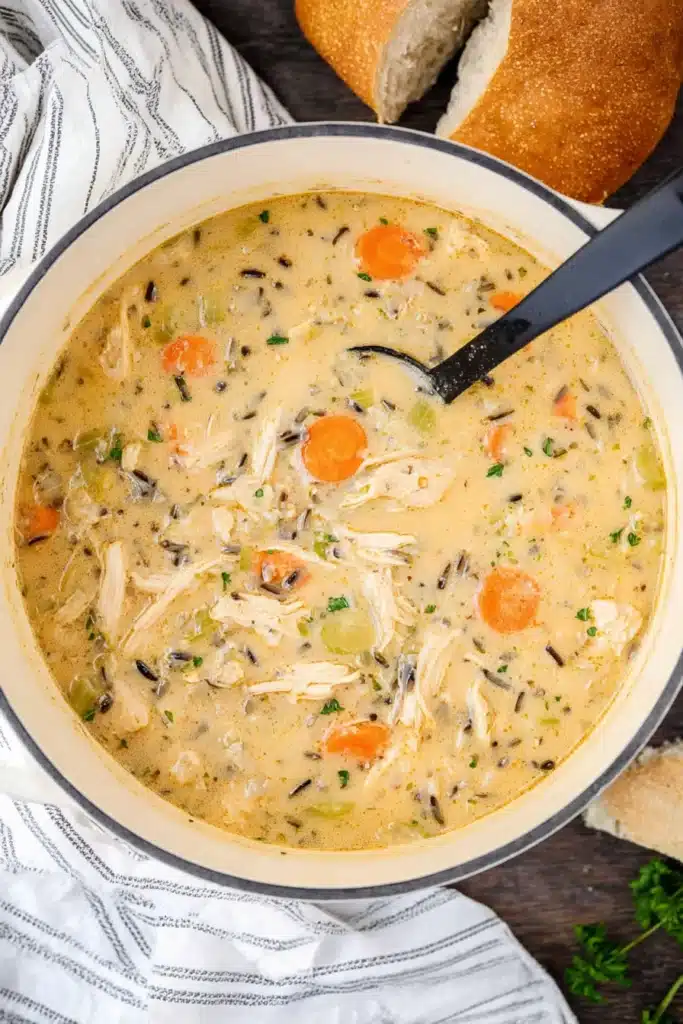 Creamy chicken tortilla soup in white pot with carrots, celery, and wild rice