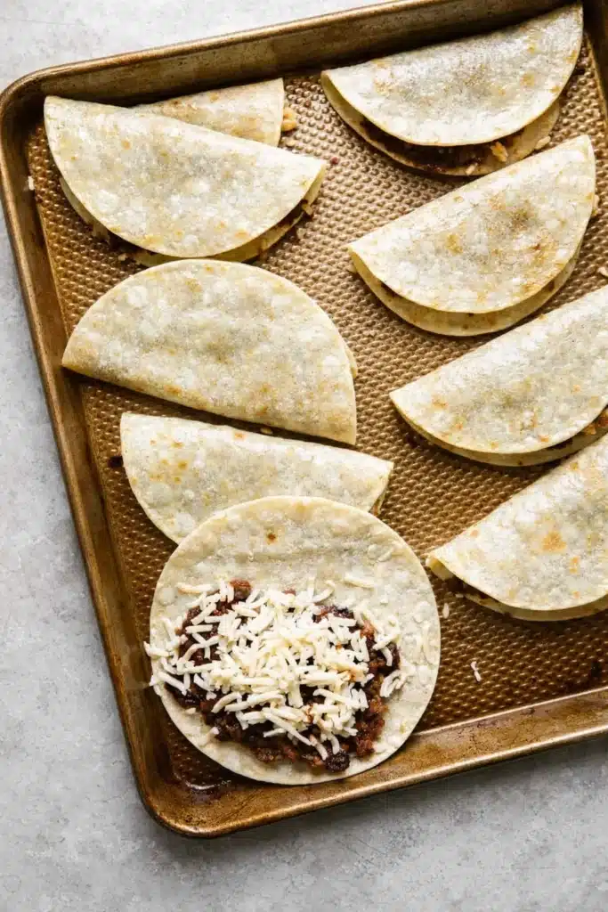 Crispy Black Bean Tacos (Vegetarian, Easily Vegan) 3 Unbaked black bean tacos with cheese on baking sheet