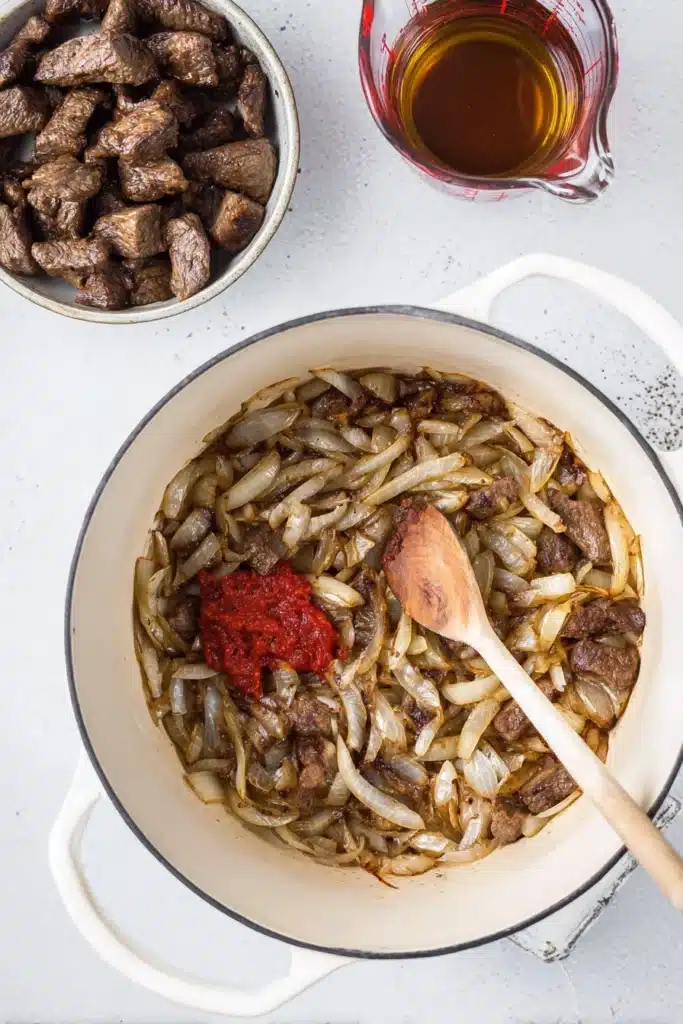 Sautéed onions and tomato paste in a Dutch oven for beef stew