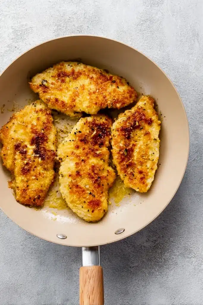 Lemon Chicken Recipe: Crispy, Tangy, and Ready in 30 Minutes 2 Golden crispy lemon chicken cooking in a beige skillet