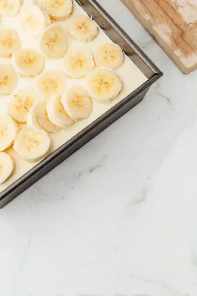No-Bake Banana Cream Pie Bars (Easy Layered Dessert with Vanilla Wafer Crust) 2 Banana pudding layer topped with banana slices in a baking pan
