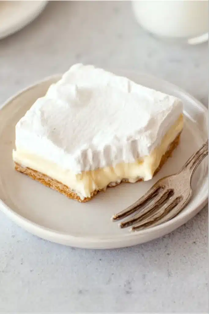 No-Bake Banana Cream Pie Bars (Easy Layered Dessert with Vanilla Wafer Crust) 3 No-bake banana cream pie bar with bite taken, showing creamy layers
