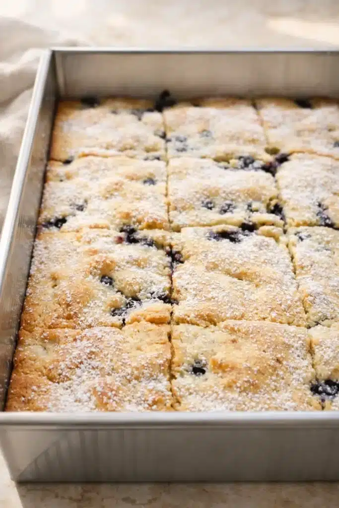 Pancake Casserole (Blueberry Baked Pancake) 4 Freshly baked blueberry pancake casserole dusted with powdered sugar in a metal pan
