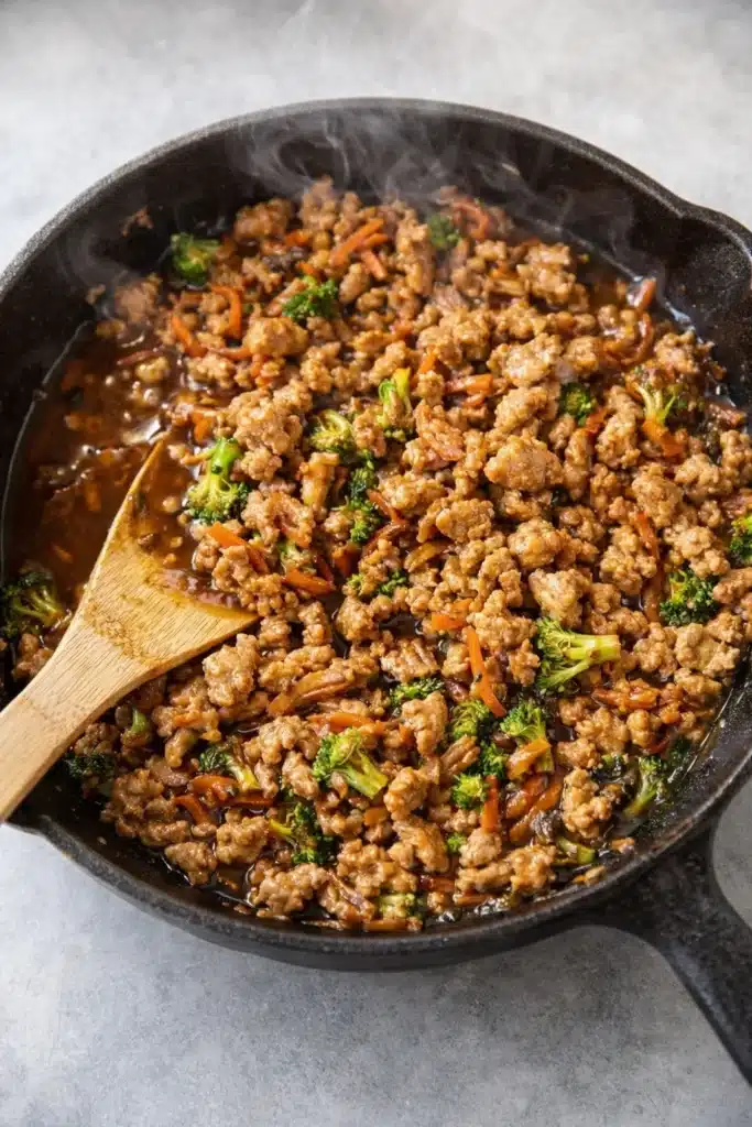 Ground turkey and vegetables cooking in teriyaki sauce in a cast iron skillet