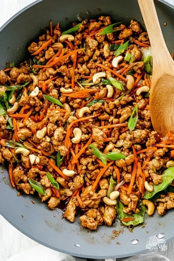Thai Chicken Lettuce Wrap filling in skillet with carrots and cashews