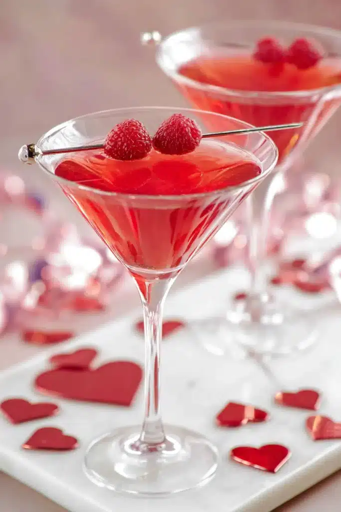 Two red love potion cocktails in martini glasses with raspberries for Valentine’s Day
