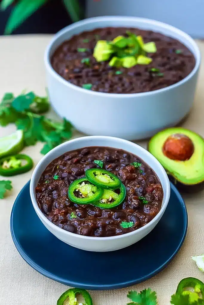 Instant Pot Black Bean Soup (Easy, Hearty & Flavorful) 3 Instant Pot black bean soup served with avocado, jalapeño, and cilantro in white bowls