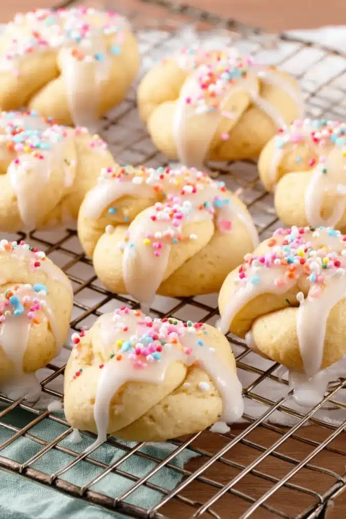Italian Easter Cookies / Uncinetti – Soft, Sweet & Traditional 2 Italian Easter Cookies Uncinetti with white glaze and colorful sprinkles on rack
