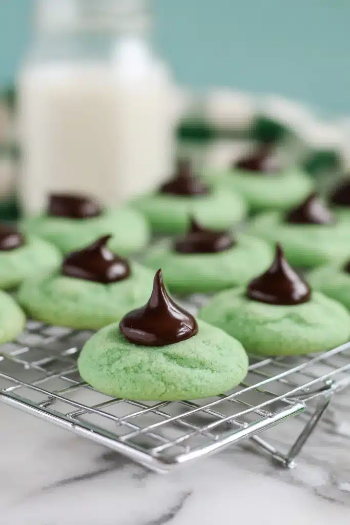 Mint Chocolate Kiss Blossom Cookies cooling on rack with glossy chocolate centers