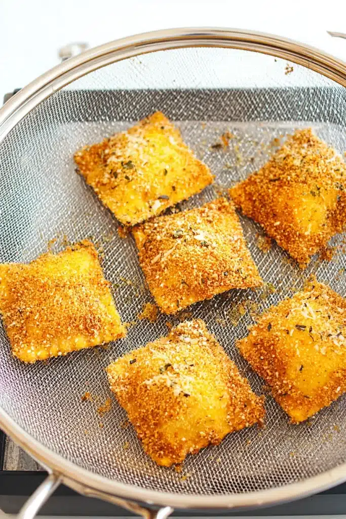 Golden toasted ravioli cooking in air fryer basket