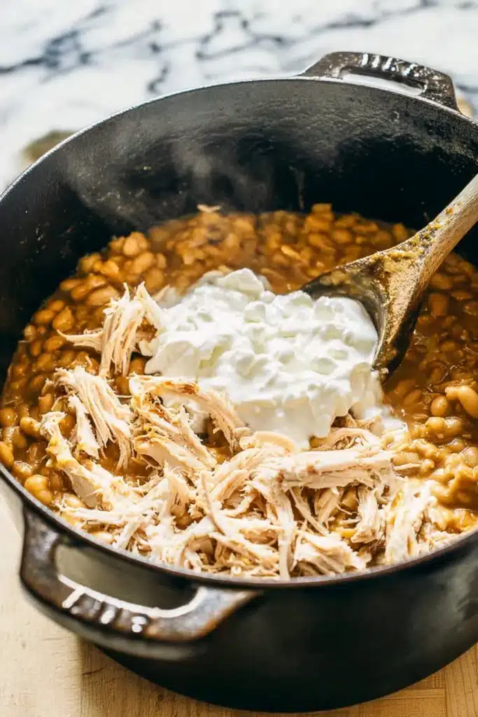 White Chicken Chili (High-Protein Comfort in a Bowl) 2 White chicken chili cooking in a pot with shredded chicken and sour cream