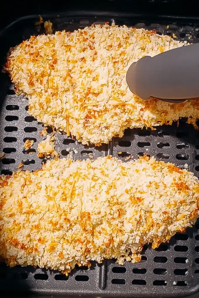Air Fryer Chicken Parmesan 2 Breaded chicken cutlets in air fryer basket for Air Fryer Chicken Parmesan