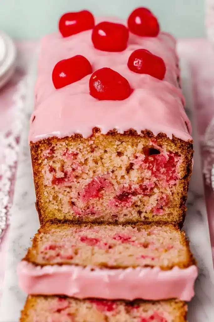 Cherry Bread Recipe That’s Sweet, Moist, and Easy 1 Cherry bread loaf with pink glaze and maraschino cherries on top, sliced to show moist crumb