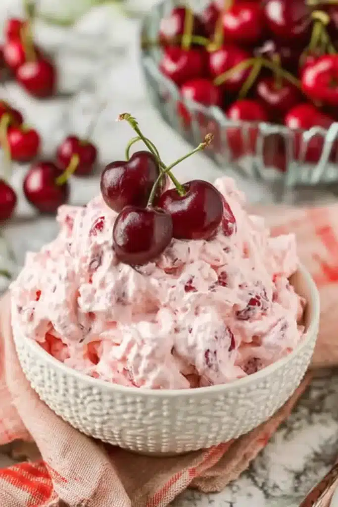 Cherry Cheesecake Fluff That’s Creamy, Easy, and Crowd Pleasing 1 Cherry Cheesecake Fluff in a white bowl topped with fresh red cherries