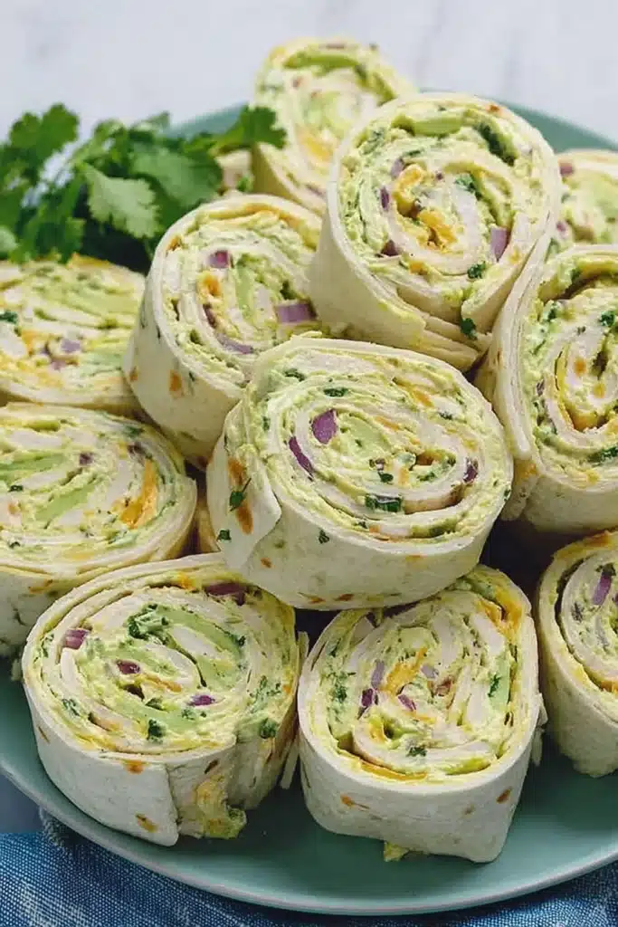 Chicken Avocado Salad Roll Ups 1 Chicken avocado salad roll ups sliced into pinwheels on a green plate