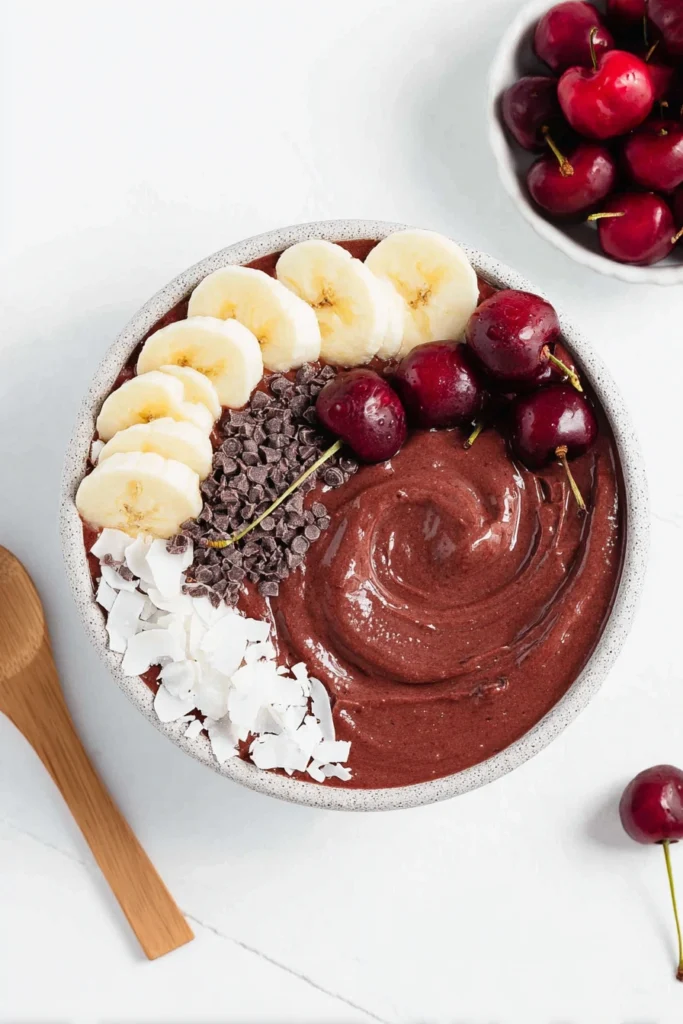 Chocolate Cherry Smoothie Bowl 1 Chocolate cherry smoothie bowl with banana slices, coconut flakes and fresh cherries