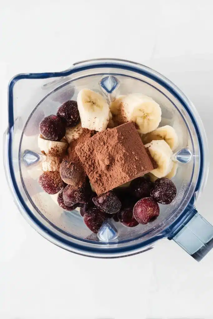 Chocolate Cherry Smoothie Bowl 2 Blender with frozen banana, cherries, and cocoa powder for chocolate cherry smoothie bowl