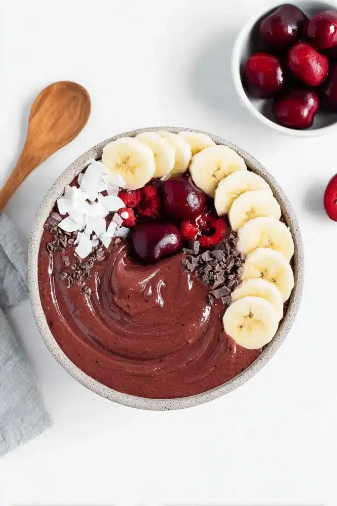 Chocolate Cherry Smoothie Bowl 3 Chocolate cherry smoothie bowl with banana slices, coconut flakes and fresh cherries