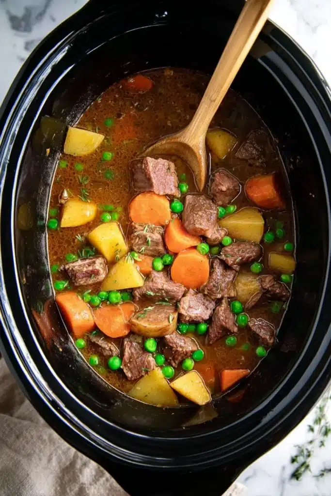 Crockpot Beef Stew Recipe: Easy, Hearty, and Comforting 3 Crockpot beef stew with beef, carrots, potatoes, and peas in slow cooker