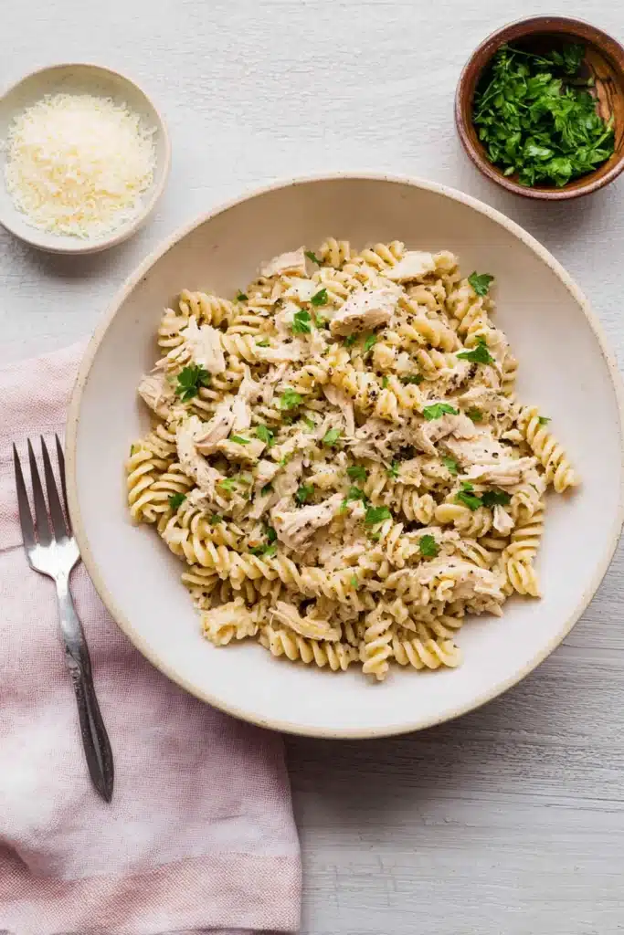 Crockpot garlic parmesan chicken pasta with rotini and parsley in a creamy sauce
